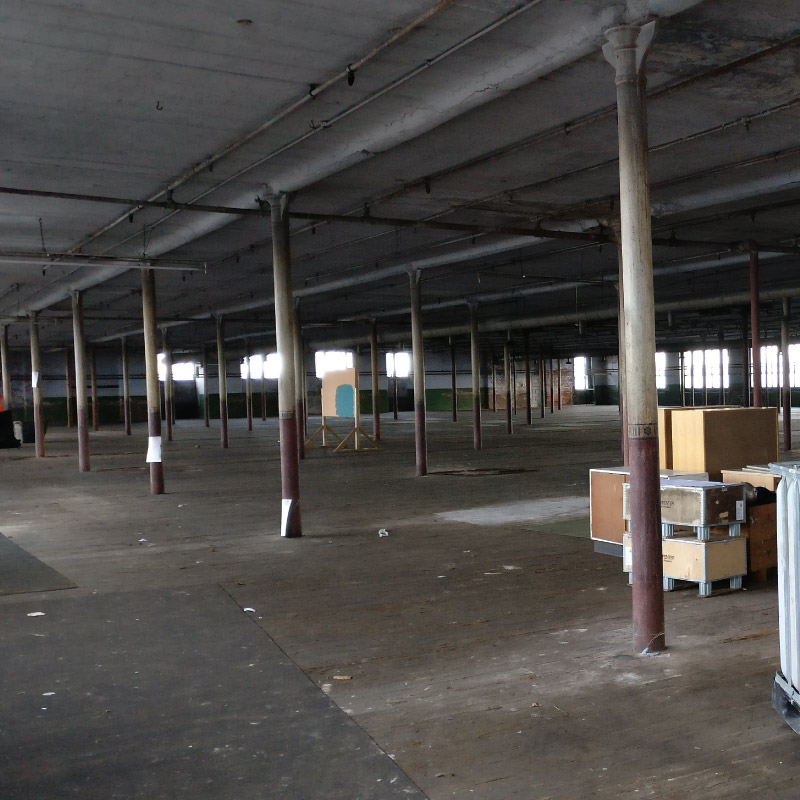 Interior open space at Leigh Spinners Mill featuring spread out structural support pillars.