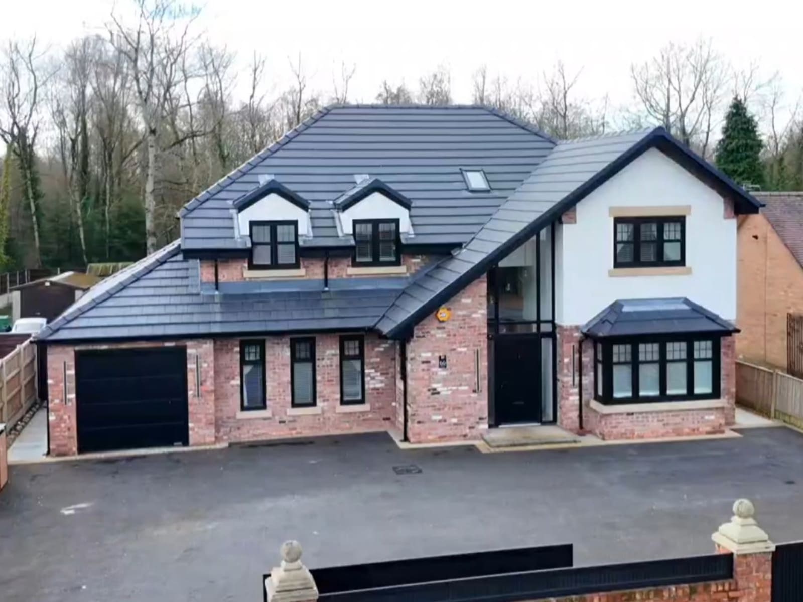 Modern new build detached home in Golborne, featuring an integrated garage, grey rooftiles, black window frames and tarmac driveway 